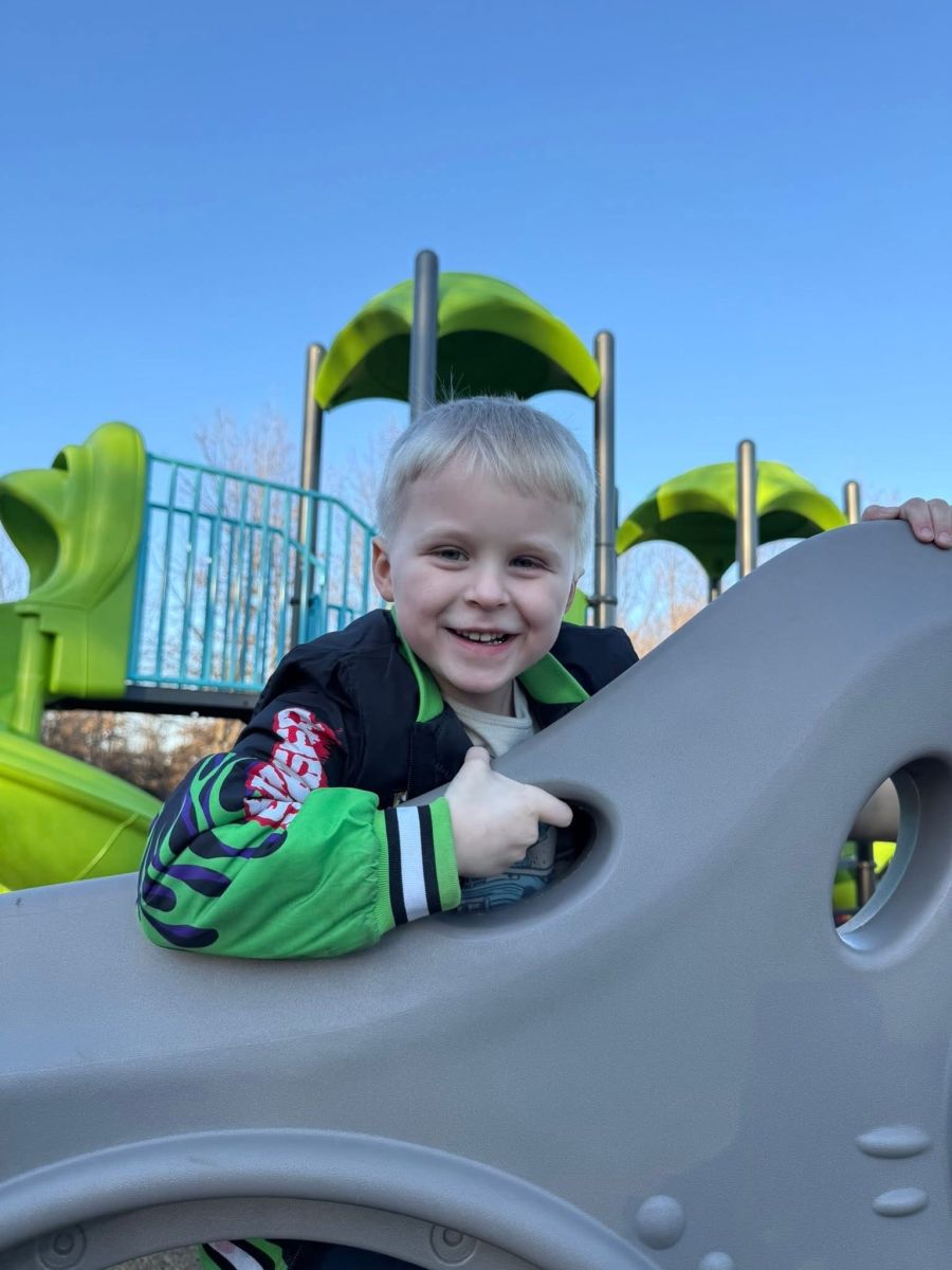 Smiling participant climbing on playground equipment at a park
